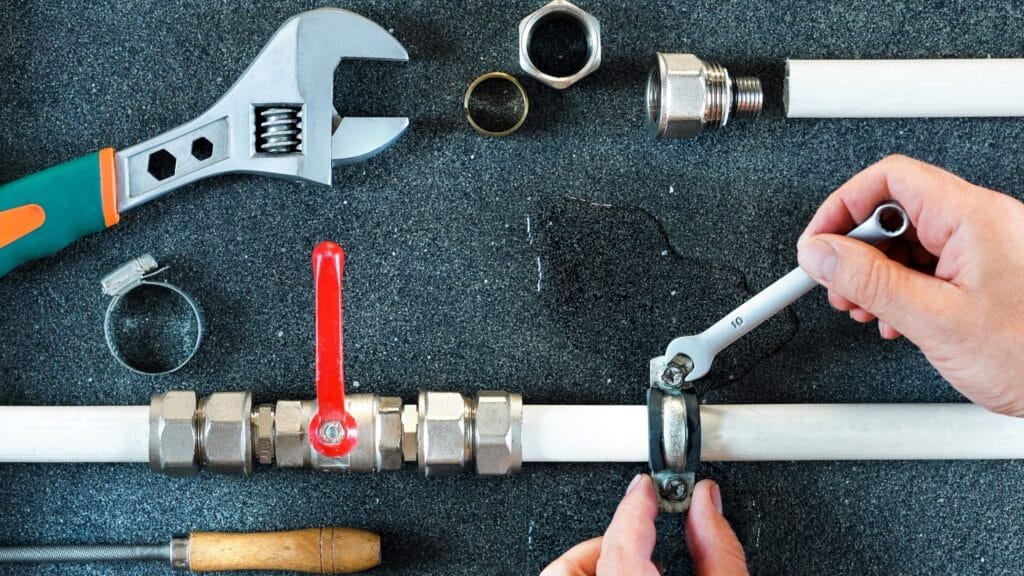 Plumber repairing a pipe valve with an adjustable wrench in Acworth