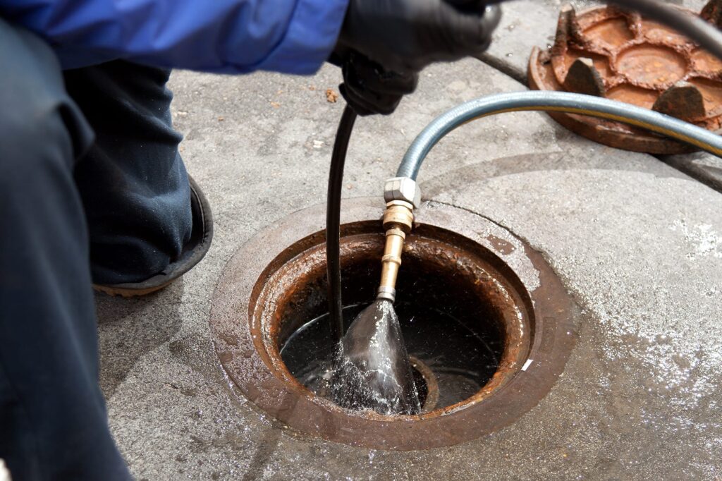 Plumber hydro jetting a sewer line through a manhole in Acworth