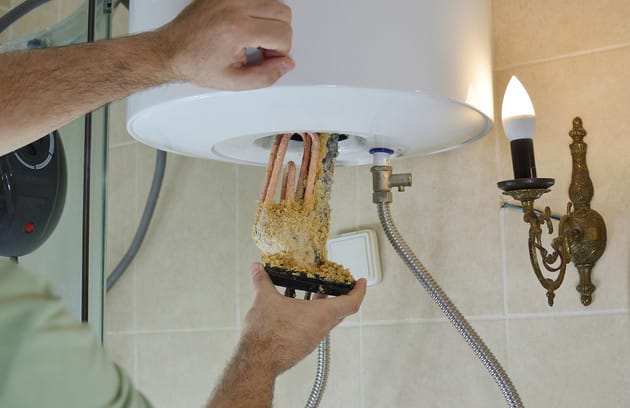 Technician removing mineral buildup from a water heater in Acworth