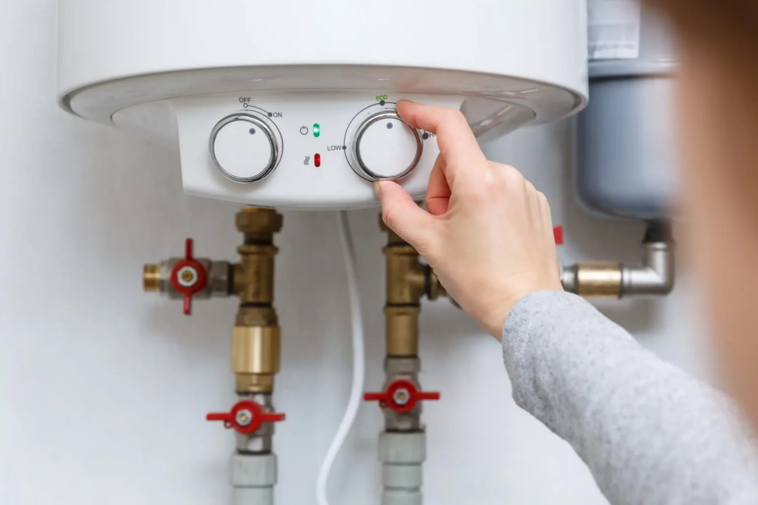 Homeowner adjusting the temperature controls on a water heater in Acworth